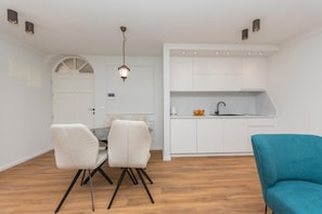 Una cocina moderna con armarios blancos y una zona de comedor con una mesa y sillas.