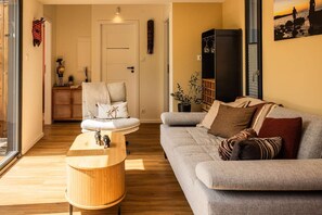 Una sala de estar con un sofá, una mesa de centro, un mueble y una puerta.