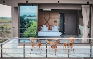 Ein Balkon mit einem Bett, zwei Korbstühlen und einem Glastisch.