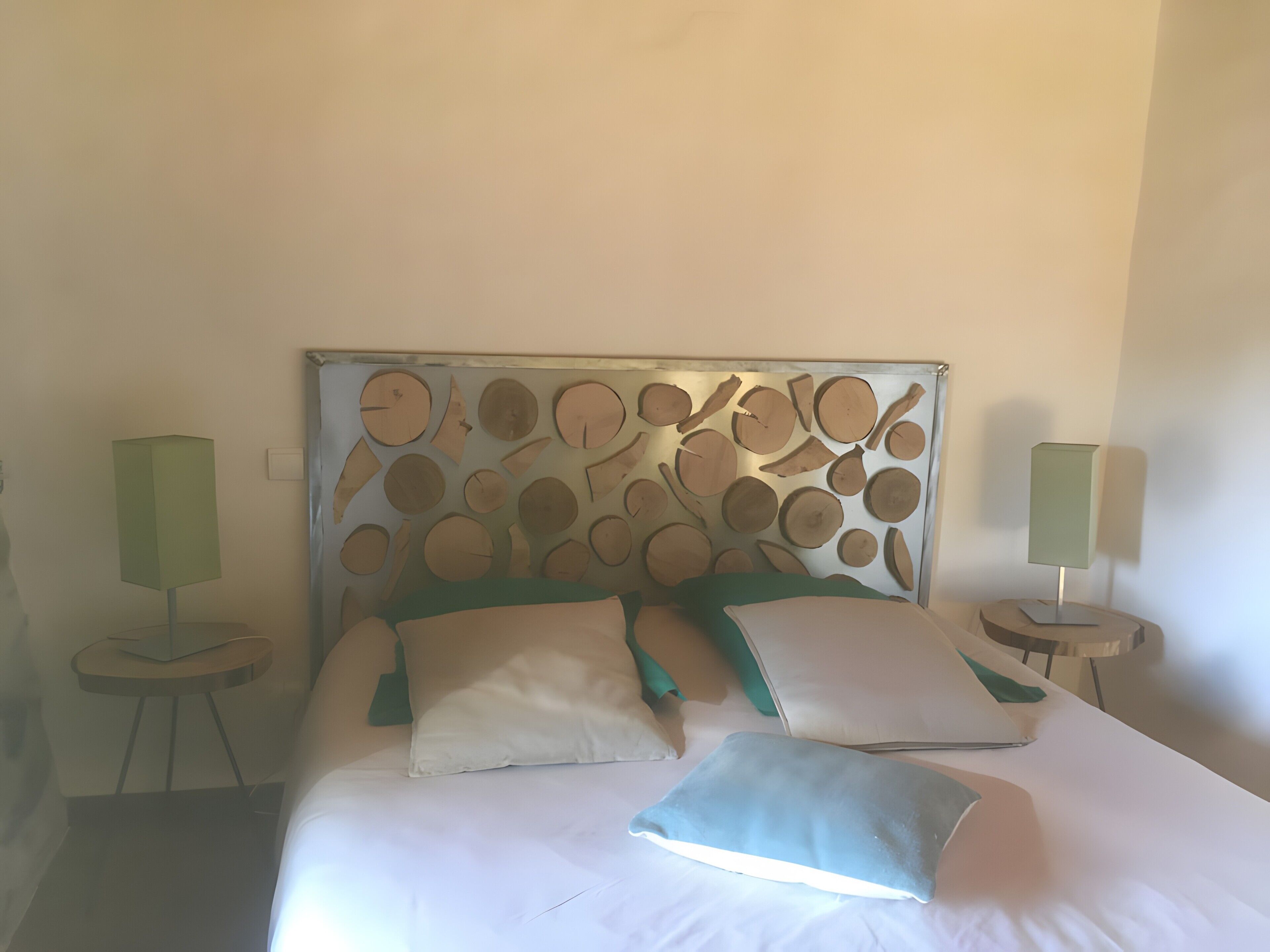 A bed with a headboard featuring circular cutouts, two bedside lamps, and multiple pillows.