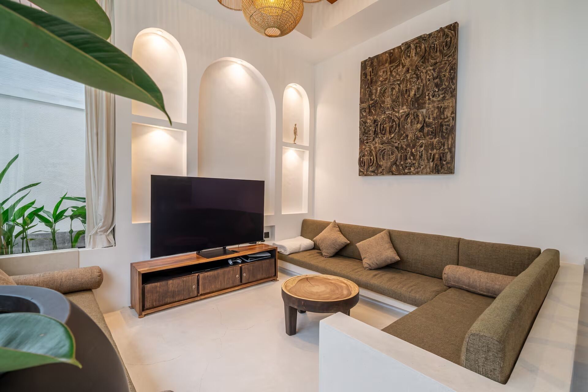 Uma sala de estar moderna com uma TV de tela plana, um sofá marrom, uma mesa de centro de madeira e um grande quadro abstrato na parede.
