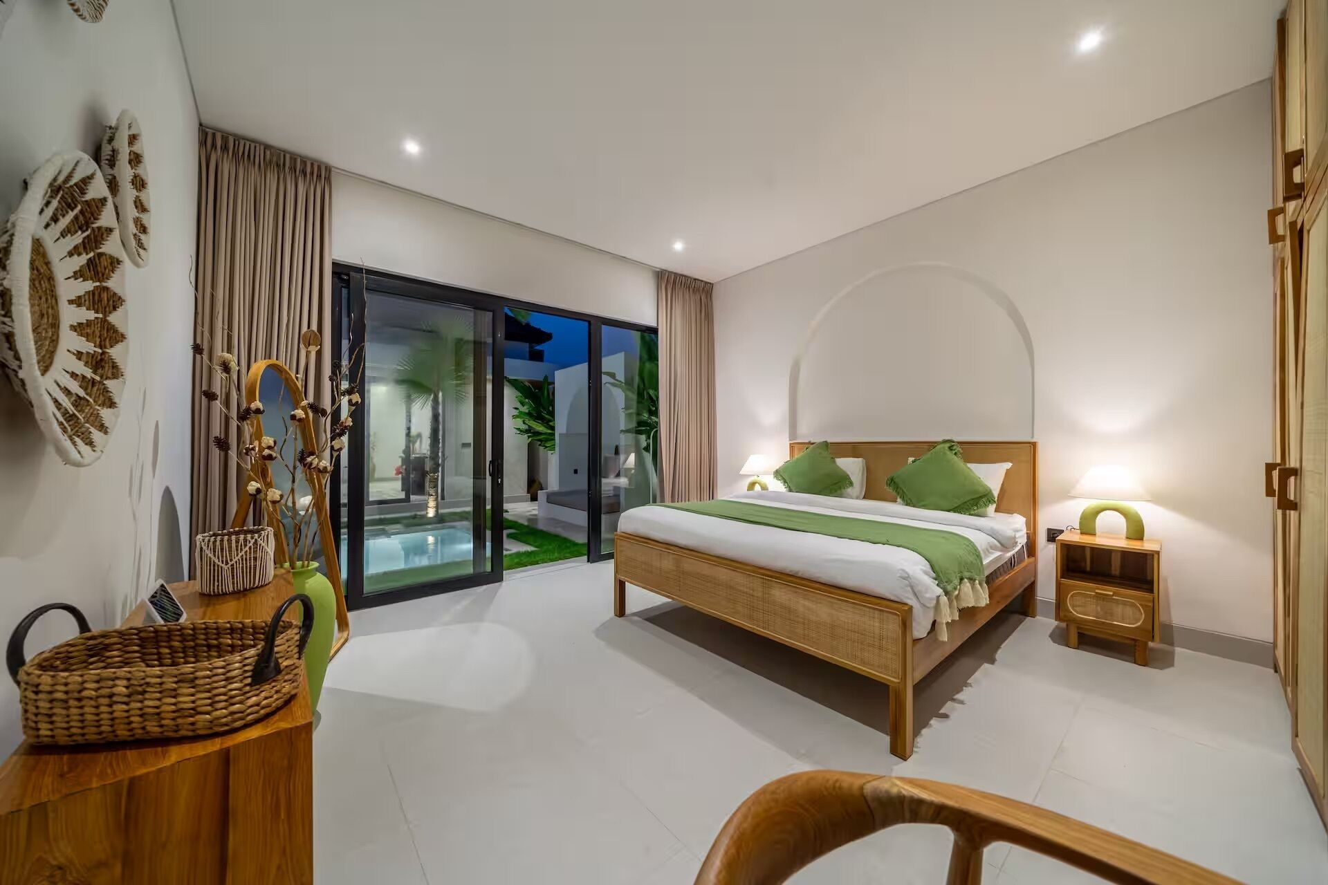Un dormitorio moderno con cama, mesita de noche, una silla y vistas al exterior.