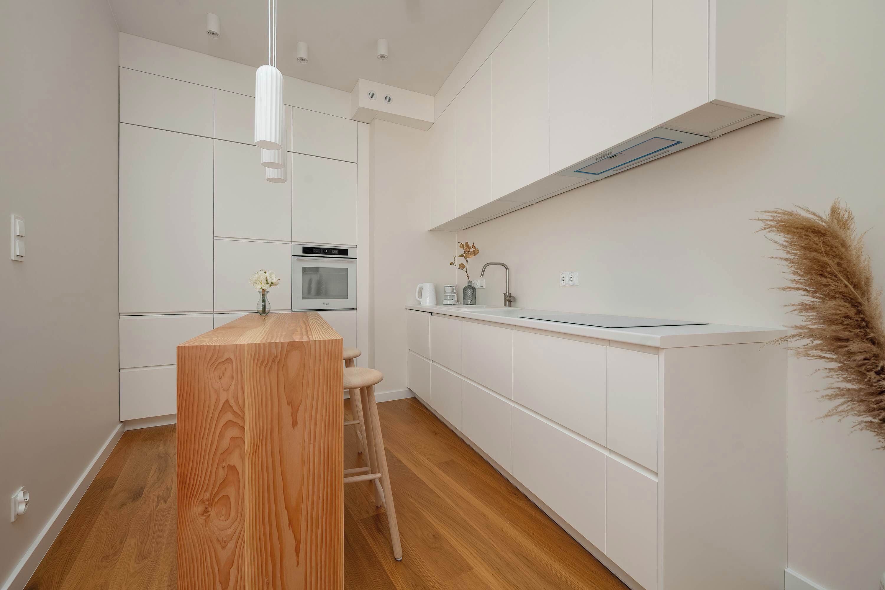 Una cocina moderna con armarios blancos, una isla de madera y un horno empotrado.
