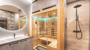 A modern bathroom with a stone wall, a large mirror, a wooden sauna, and a shower. - Lorenzer Penthouse (Scheifling)
