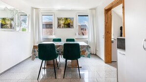 A dining area with a table and chairs, large windows, and a view of buildings outside. - Apartment 'Gemütliche' with Wi-Fi (Göppingen)