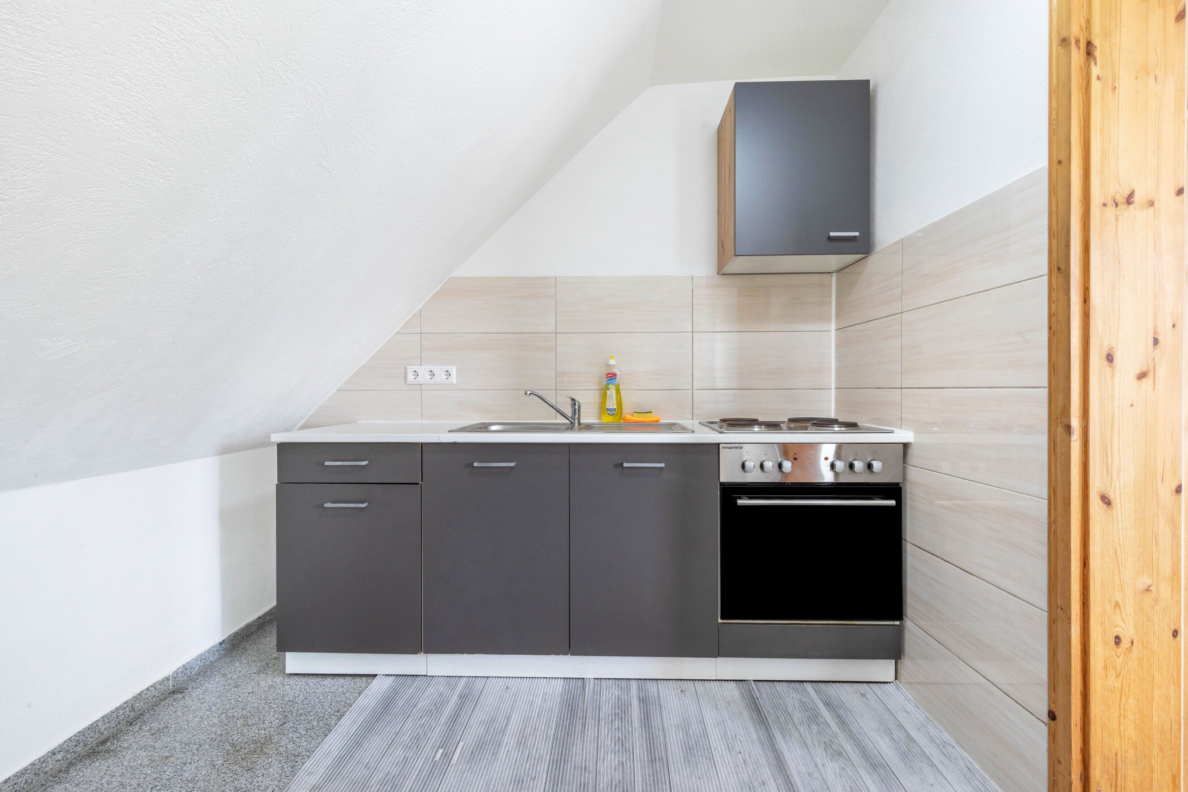 A modern kitchen with a built-in oven, a sink, and a cabinet above the stove.