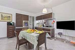 A modern kitchen with a dining area, a flat-screen TV, and a laptop on a cart. - Maison Clelie With Garden - 200 M From Sea (Massa)