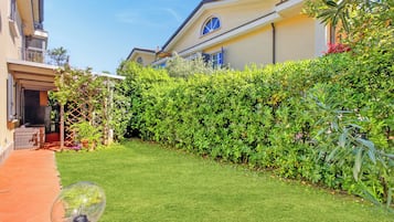 A well-maintained garden with a clear pathway, a hedge, and a building with a balcony.