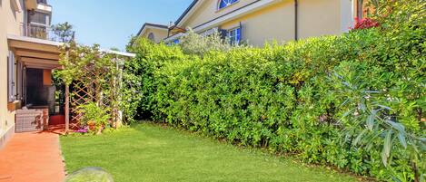 Un jardin bien entretenu, avec un chemin bien défini, une haie et un bâtiment doté d’un balcon.