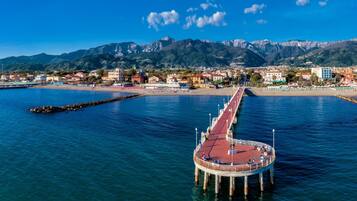 A pier extending into a calm sea with a mountainous backdrop.
