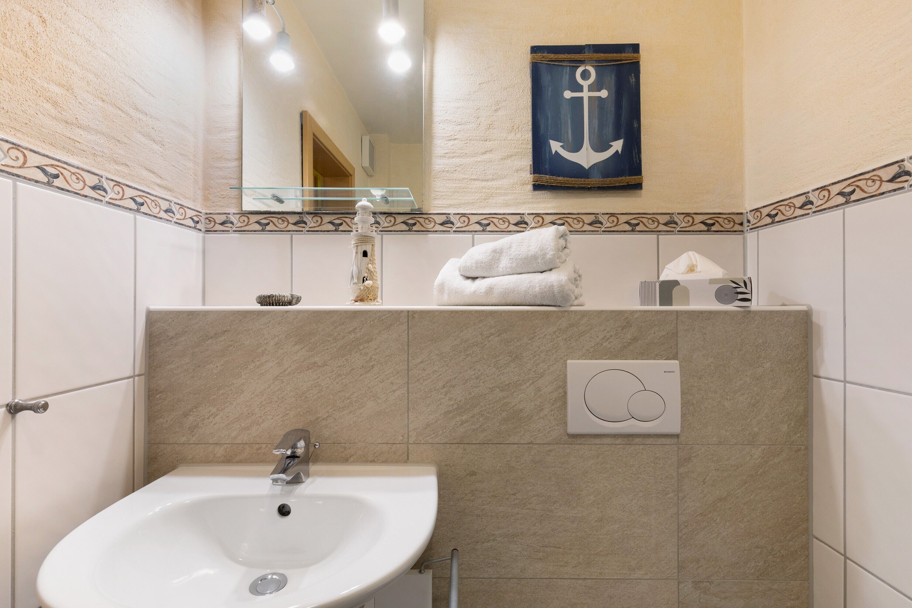 Ein Badezimmer mit Waschbecken, Spiegel, Handtuch und dekorativen Wandfliesen.