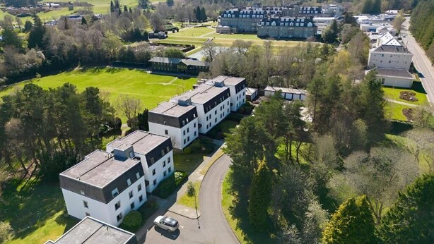Vue aérienne d’un quartier résidentiel avec des bâtiments modernes, une route et des espaces verts environnants.