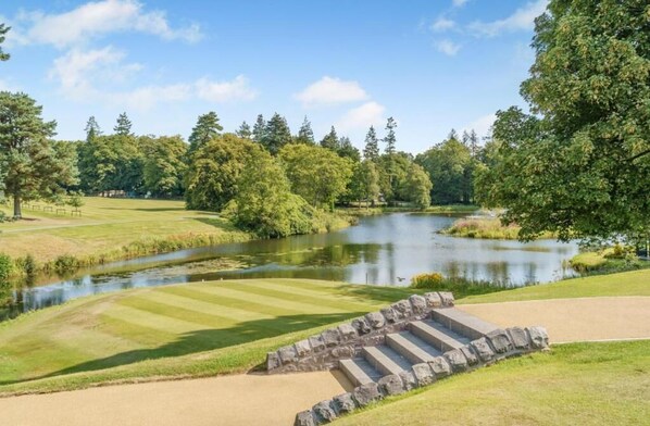 A golf course with a pond, stone steps, and a clear sky.
