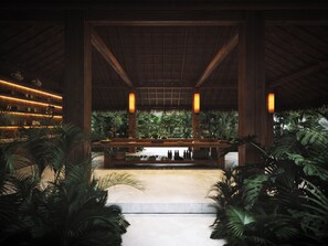 Zona de bar con techo de madera, estanterías con botellas y plantas tropicales.