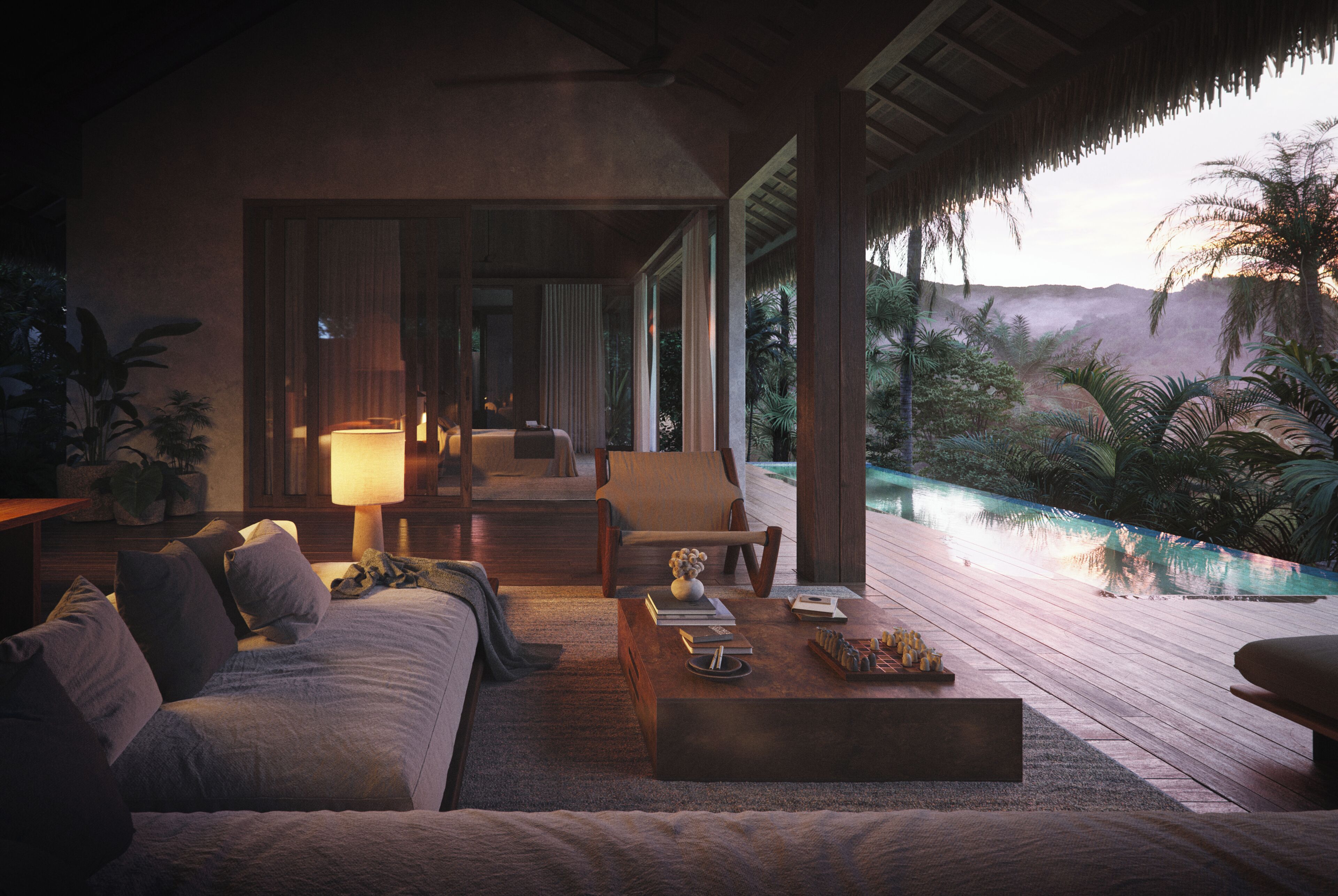 A cozy room with a sofa, a coffee table, and a lamp. There is a view of a pool and greenery outside.