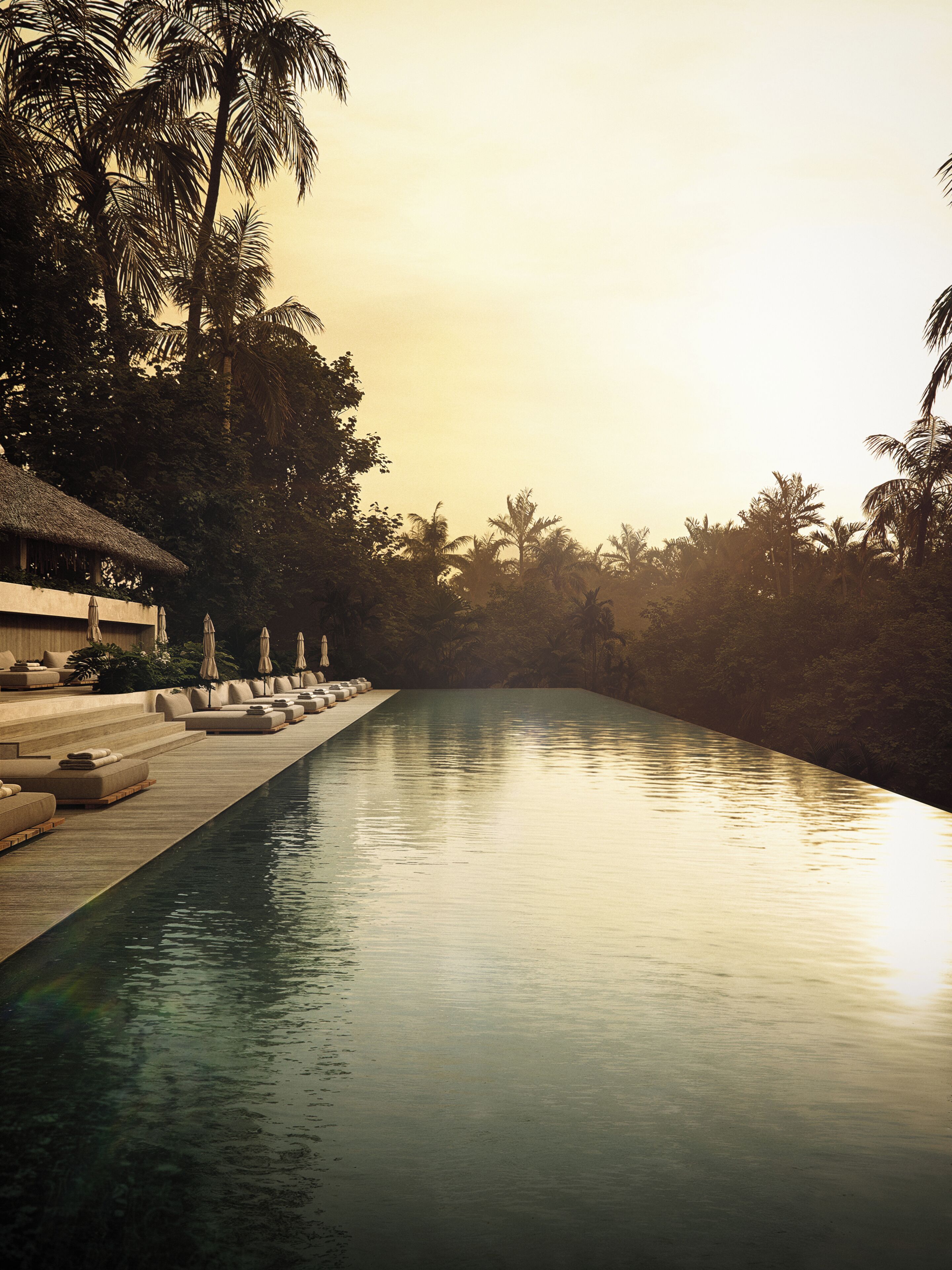 A pool with lounge chairs and umbrellas, surrounded by palm trees.