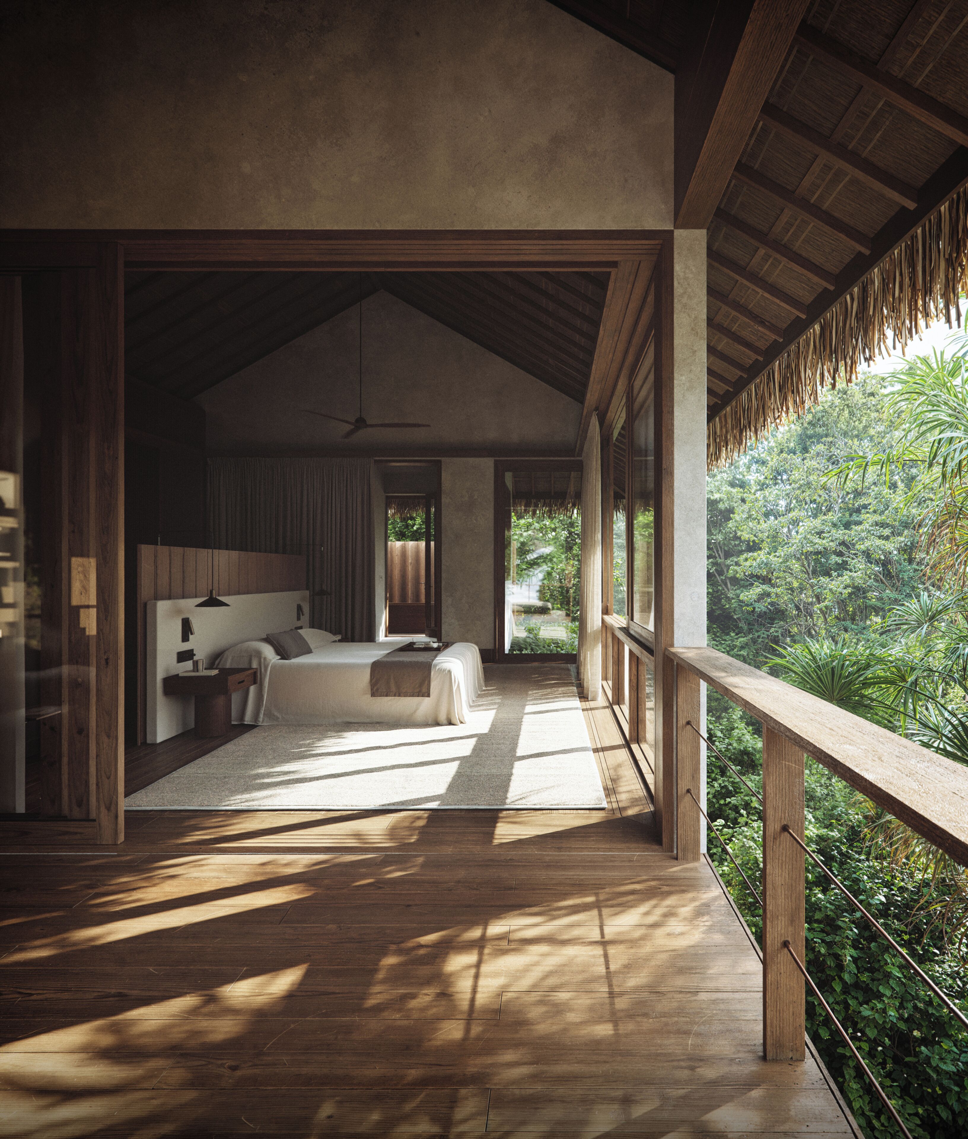 A spacious bedroom with a large bed, a bedside table, and a ceiling fan. There is a balcony with a wooden railing overlooking a lush garden.