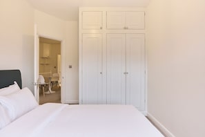 Ein Schlafzimmer mit einem Bett, einem weißen Kleiderschrank und einem durchgegangenen Tür erkennbaren Badezimmer.