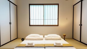 A room with a bed, two bedside tables, a window with vertical blinds, and sliding doors on either side. - Irodori Hotel AKANE (fukuokashi,hakataku,kamigofukumachi)