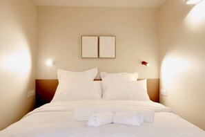A hotel room with a bed, two wall-mounted light fixtures, and a framed picture above the bed. - Babylon Popincourt 12 (Paris)