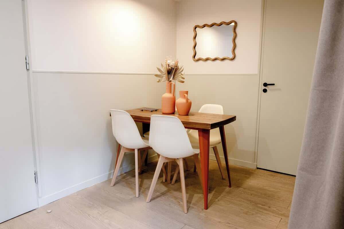 Un comedor con una mesa, sillas y un florero con flores secas.