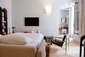 Ein modernes Hotelzimmer mit Bett, Schreibtisch, Stuhl, Fernseher und einem durchgehenden Tür zugehörigen Badezimmer.