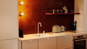 Eine moderne Küche mit einer weißen Spüle, zwei Wasserkochern, einer Kaffeemaschine und einem Toaster.