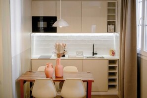 A modern kitchen with a white countertop, a built-in microwave, and a hanging pendant light. - Babylon Popincourt 22 (Paris)