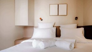 Habitació d'hotel amb llit, dues taules de nit i una làmpada de paret.