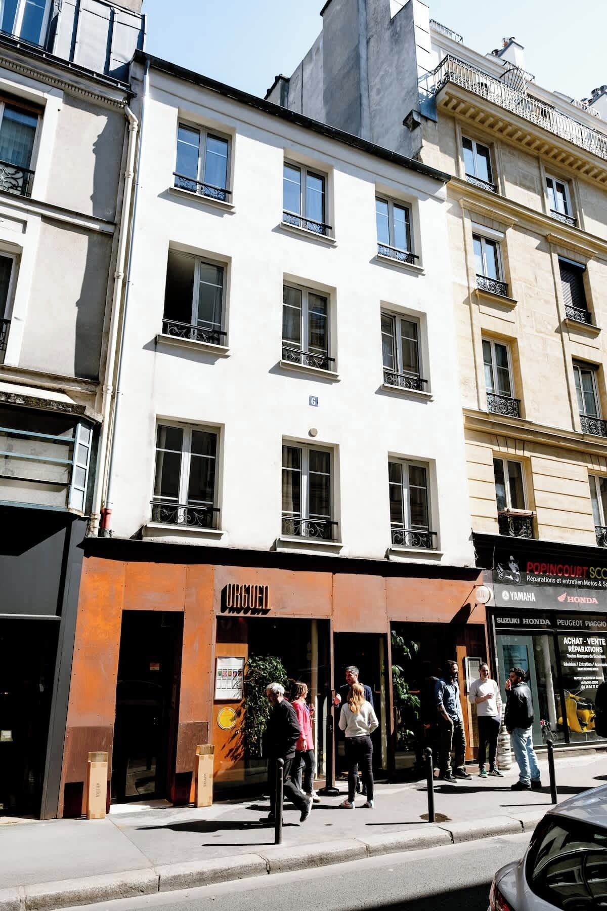 A multi-story building with a storefront labeled 'URGENCE' and various signs for automotive services.