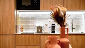 A kitchen with wooden cabinets, a microwave, a toaster, and a vase with flowers. - Babylon Popincourt 13 (Paris)