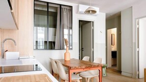 Eine moderne Küche mit Holztisch und -stühlen, einem eingebauten Backofen und einem Fenster mit Vorhängen.