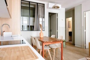 Eine moderne Küche mit Holztisch und -stühlen, einem eingebauten Backofen und einem Fenster mit Vorhängen.