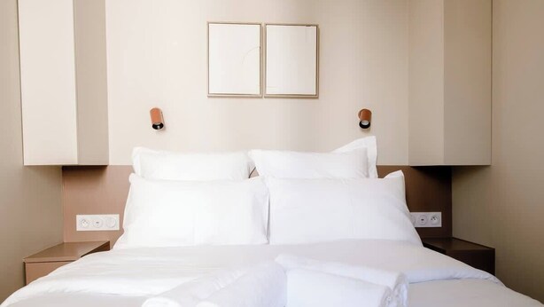 Ein Hotelzimmer mit einem Bett, zwei Nachttischen und einer Wandleuchte.