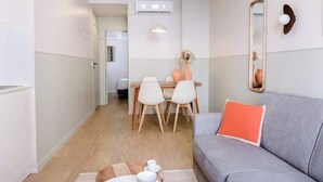 Ein modernes Wohnzimmer mit einem grauen Sofa, einem Holzesstisch mit Stühlen, einem kleinen Teppich und einem Spiegel an der Wand.