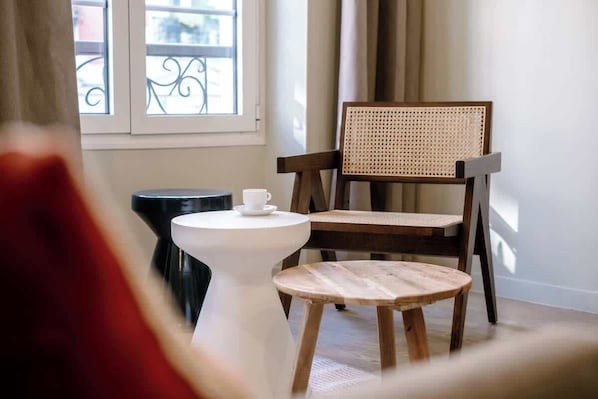 Ein Zimmer mit einem Holzhocker, einem weißen Tisch und einem Fenster mit Blick.