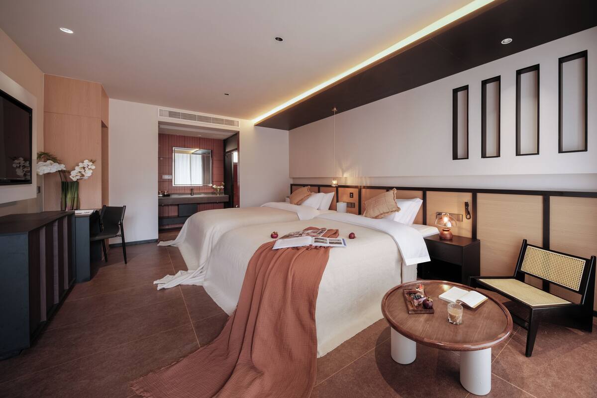 Una habitación de hotel con cama, mesita de noche, silla y escritorio con ordenador.