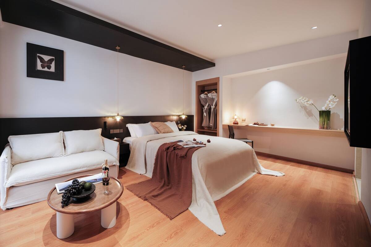 Una habitación de hotel moderna con una cama, un sofá, una mesa de centro y un televisor.