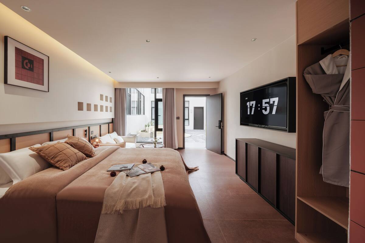 Una habitación de hotel moderna con una cama grande, televisión, armario y vistas al exterior.
