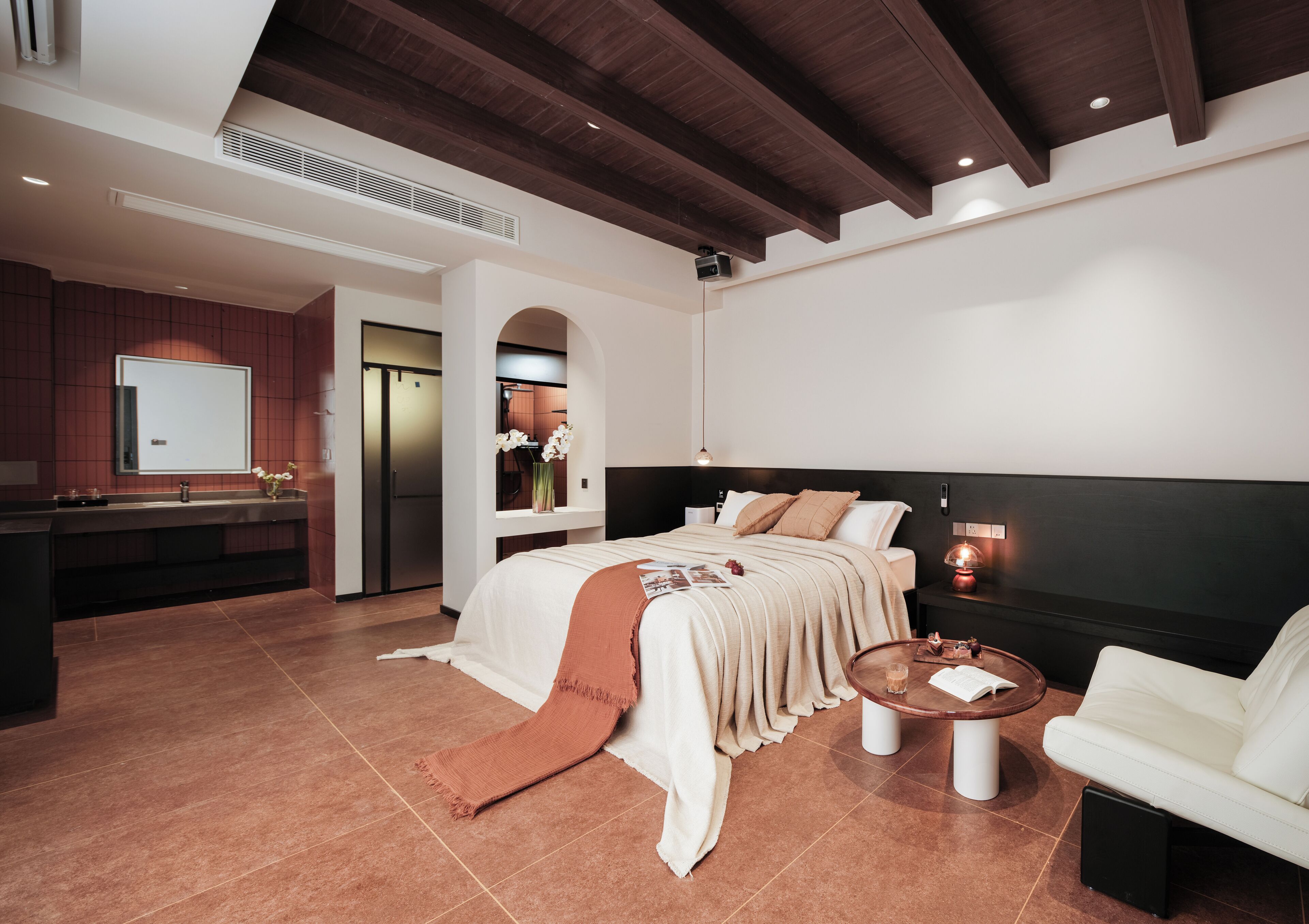 Una habitación de hotel moderna con cama, sofá, mesa de centro y zona de cocina.