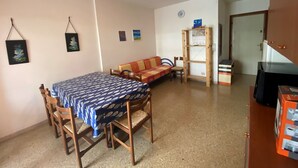 Un espacio habitable compacto con una mesa de comedor, sillas, un sofá, una estantería de madera y un televisor.