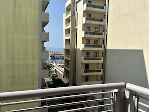 Ein Hochhaus mit mehreren Balkonen, Blick auf einen Strand und einem klaren Himmel.
