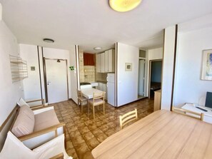 Ein kompakter Wohnraum mit Essbereich, Küchenzeile und einem separaten Zimmer mit Bett.