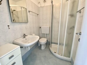 A bathroom with a shower, toilet, sink, and a mirror. - Modern beachfront stay with parking (Bibione)