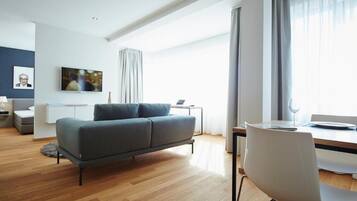 Deluxe-Apartment | Wohnbereich | 55-Zoll-Flachbildfernseher mit Kabelempfang, Arbeitsbereiche