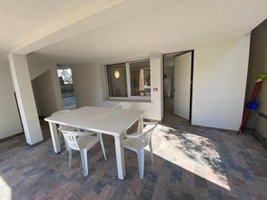 Ein Zimmer mit weißem Tisch und Stühlen, einem Fenster, einer Tür und einem an der Wand angelehnten Mop.