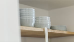 A shelf with stacked white plates and bowls.