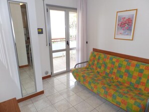 A room with a sofa, a sliding glass door, a framed picture on the wall, and a tiled floor. - Space and comfort for everyone near the beach (Bibione)