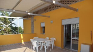 A covered patio with a table and chairs, a sliding glass door, and a tiled floor. - Equipped apartment for group getaways in Bibione (Bibione)
