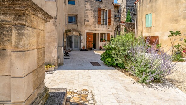 A narrow alleyway with stone buildings, a sign reading 'PLACE DU CHATEAU,' and a small courtyard with plants. - Guest Room “Coquelicot” with Wi-Fi and Air Conditioning (Domazan)
